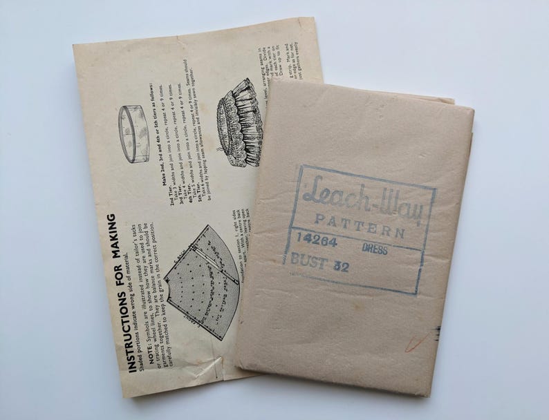 May include: A vintage Leach-Way dress pattern, with sewing instructions and illustrations. The pattern is in a tan paper envelope, marked "Leach-Way PATTERN 14264 DRESS BUST 32". The instructions are printed on aged paper.