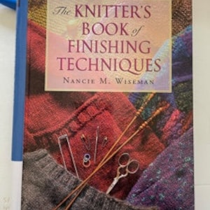 May include: The Knitter's Book of Finishing Techniques by Nancie M. Wiseman, a book with a colorful knitted fabric cover featuring knitting needles, scissors, and yarn.