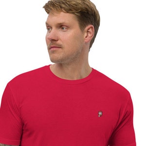 May include: A red short-sleeved t-shirt with a small embroidered design on the left chest.