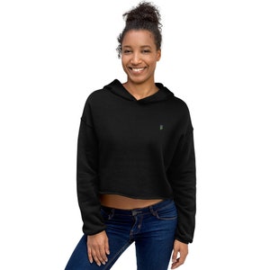 May include: A black cropped hoodie with a small, colorful graphic on the front. The hoodie has a drawstring hood and long sleeves.