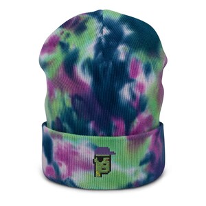 May include: A green, blue, and purple tie-dye beanie with a pixelated character wearing a purple hat embroidered on the front.