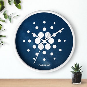 May include: A white clock with a blue face and white hands. The clock face has a white design of a circle with smaller circles around it. The text "CARDANO" is printed below the design.