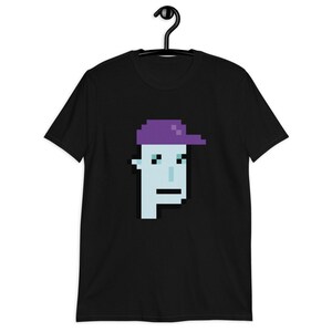 May include: Black t-shirt with a pixelated image of a person wearing a purple hat. The person has a blue face and a neutral expression.