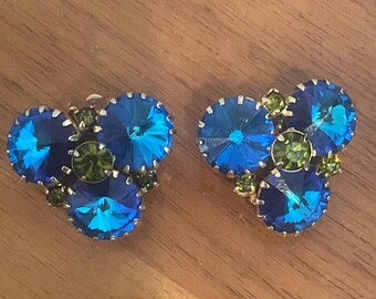 May include: A pair of blue and green rhinestone earrings. The earrings are made of gold-toned metal and feature a cluster of blue and green rhinestones.