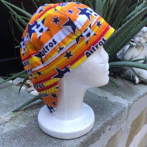 Könnte beinhalten: Orange, gelbe, rote und blaue Schweißkappe mit einem Sternen- und "Astros"-Muster.
