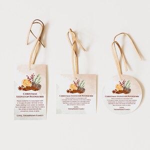 May include: Three Christmas stovetop potpourri tags with light tan ribbon loops. Each tag features a watercolour illustration of orange slices, cinnamon sticks, pinecones, and greenery, with printed instructions and the text, Love, Thompsons Family.