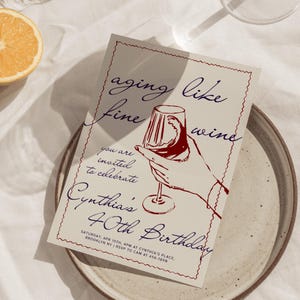May include: A birthday invitation with the text "aging like fine wine" and "Cynthia's 40th Birthday". The invitation features a hand holding a wine glass with red wine, and is on a beige background.