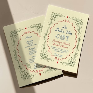 May include: Two cream-colored event invitations with red and green floral border designs. The invitations feature the text "La Dolce Vita" and "Penelope Rossi's Bridal Shower" in blue and red script. Menu items are listed on the left invitation.