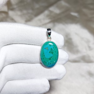 May include: A silver pendant with a green and blue oval-shaped gemstone. The gemstone has a swirling pattern.