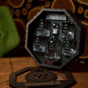 May include: A dark wooden decanter set with a decanter and six glasses, all etched with a "W" logo and the name "Wagner". The set is displayed in a dark wooden octagonal box. A wooden coaster with the "Wagner" logo is in front.