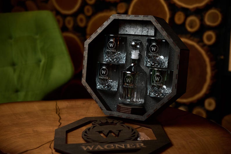 May include: A dark wooden decanter set with a decanter and six glasses, all etched with a "W" logo and the name "Wagner". The set is displayed in a dark wooden octagonal box. A wooden coaster with the "Wagner" logo is in front.