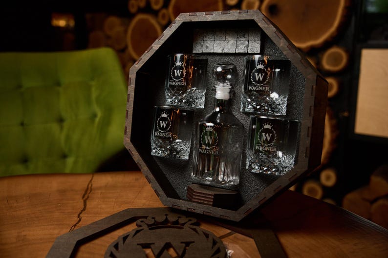 May include: A wooden box set containing a decanter and four glasses, all etched with the letter "W" inside a crown and the name "Wagner". The set also includes ice stones. The glasses and decanter are clear.