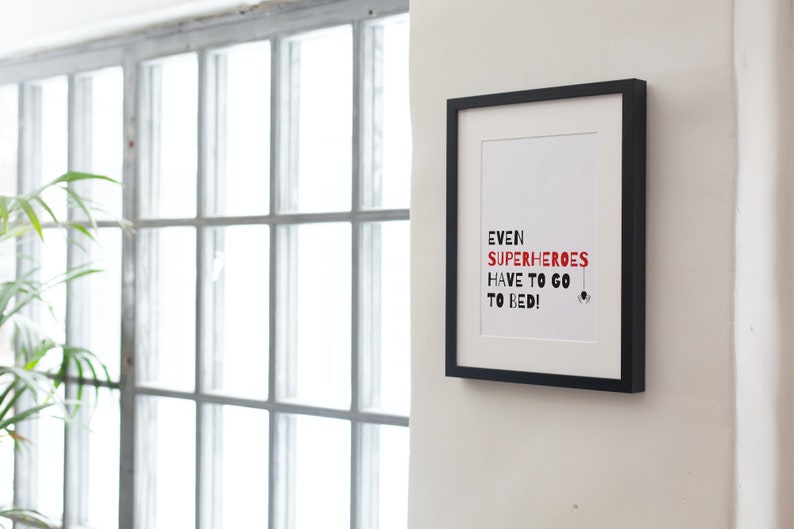 May include: A black framed print with a white background and red text that reads "Even superheroes have to go to bed!" with a small black spider graphic at the bottom.
