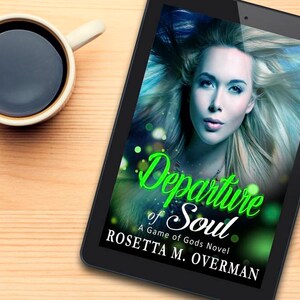 May include: A digital tablet displays the cover of the book "Departure of Soul: A Game of Gods Novel" by Rosetta M. Overman. The cover features a woman with blonde hair and the title in green script. A cup of coffee sits to the left.