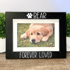 May include: Black picture frame with a white paw print and the word "BEAR" above a photo of a golden retriever puppy. The bottom of the frame says "FOREVER LOVED".