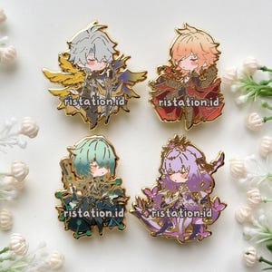 May include: Four enamel pins featuring anime-style characters in various colors. Each pin has a gold outline and the text "ristation.id". The characters have detailed outfits and accessories, with a cute, chibi-like design.