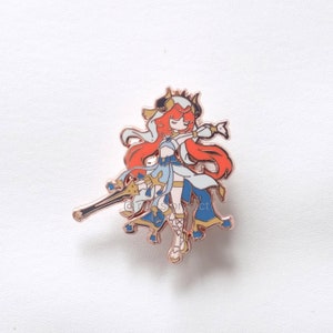 Puede incluir: Pin de esmalte de oro rosa con un personaje de dibujos animados con cabello rojo largo, vestido con un vestido blanco y azul y sosteniendo una espada. El personaje tiene una corona y cuernos en la cabeza.