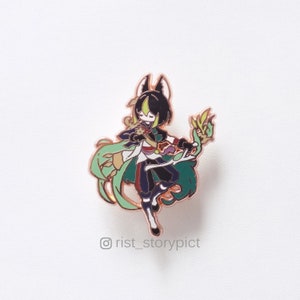 Puede incluir: Un pin de esmalte verde, negro y dorado con un personaje de dibujos animados con cabello negro y un atuendo verde y dorado. El personaje sostiene un bast&oacute;n verde y dorado. El pin est&aacute; sobre un fondo blanco. &copy;rist_storypict