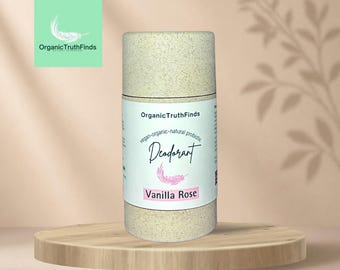 May include: A cylindrical deodorant stick with a speckled beige, paper-like texture. The white label features the text OrganicTruthFinds, vegan-organic-natural probiotic Deodorant, a pink feather graphic, and the scent name Vanilla Rose in pink.