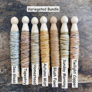 Pu&ograve; includere: Un Variegated Bundle di sette rocchetti di legno avvolti nel filo. Le etichette riportano Sea Glass, Tapestry, Homestead, Autumn Mist, Blush Fawn, Sunday Morning e Twilight Copper. Ogni rocchetto presenta una base e una cima in legno.