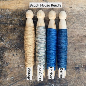 Pu&ograve; includere: Quattro mollette da bucato in legno avvolte da filato, etichettate Beach House Bundle. I colori del filato sono Vintage, un beige chiaro; Sea Glass, un grigio-verde variegato; Harbor, un blu brillante; e Denim, un blu scuro.