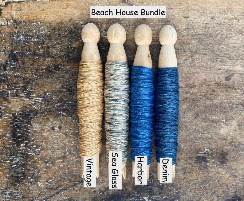 Pu&ograve; includere: Quattro mollette da bucato in legno avvolte da filato, etichettate Beach House Bundle. I colori del filato sono Vintage, un beige chiaro; Sea Glass, un grigio-verde variegato; Harbor, un blu brillante; e Denim, un blu scuro.