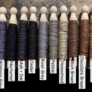 Pu&ograve; includere: Quattordici mollette da bucato in legno avvolte con fili di vari colori, etichettate Evening Violet, Aubergine, Wisteria Grey, Nocturnal, Ash + Ink, Cinder, River Grey, Pebble, Homestead, Rich Brown, Chocolate Brown, Blush Fawn, Bourbon e Mocha Bark.