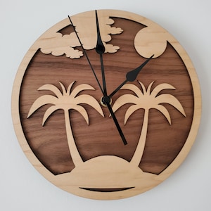 May include: A wooden wall clock with a brown and light wood design. The clock features a palm tree silhouette and a sun in the background. The clock hands are black.