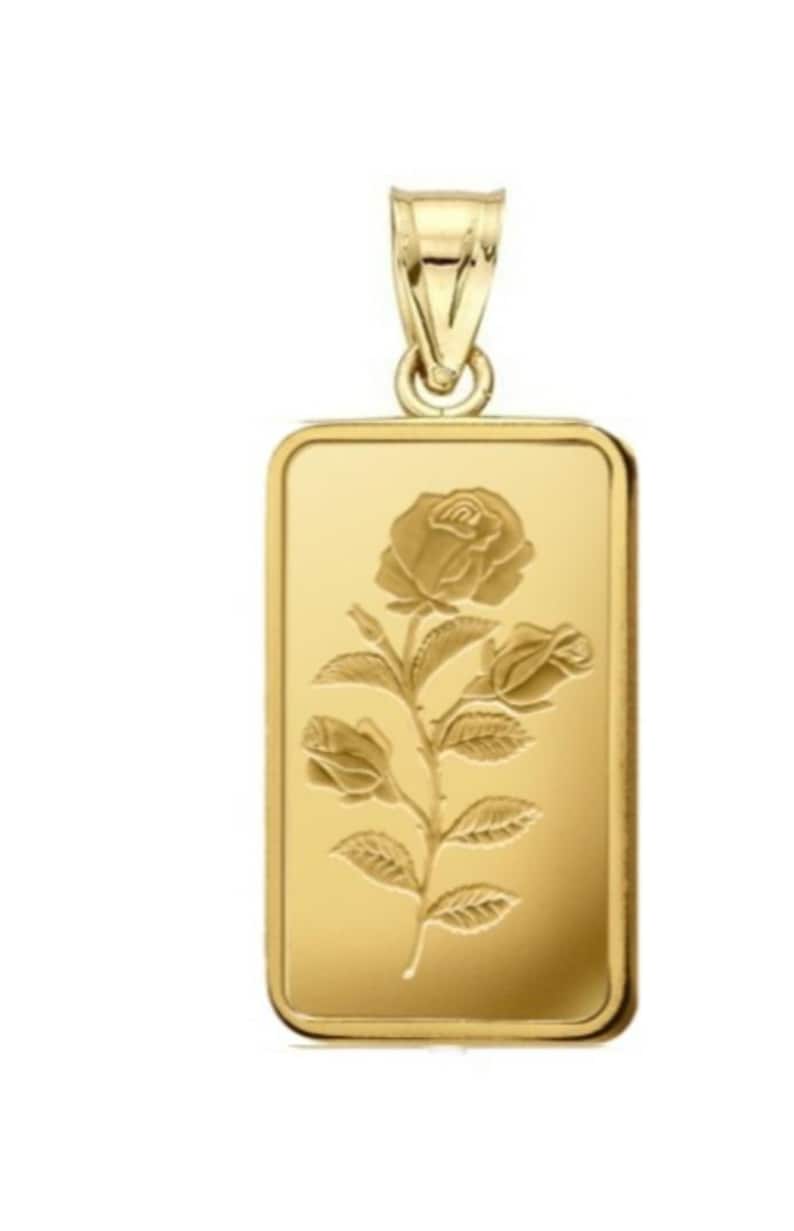 May include: A gold pendant in the shape of a rectangular bar with a rose design. The rose is engraved on the front of the pendant.