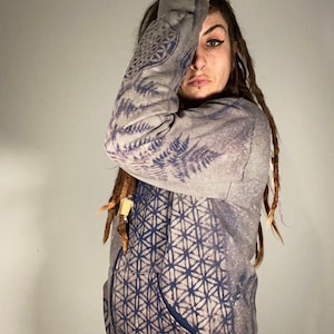 May include: A gray hoodie with a blue and white geometric pattern and fern leaf design. The hoodie has a drawstring hood and a kangaroo pocket.