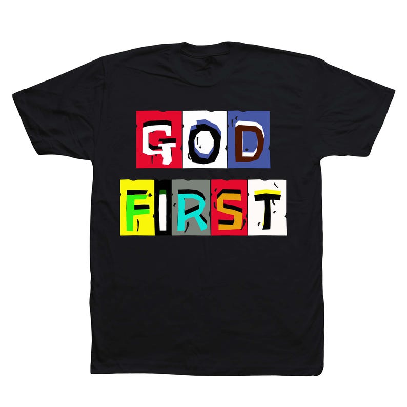 May include: Black t-shirt with the words "GOD FIRST" in a colorful, block letter design. The text is arranged in two rows, with each letter in a different color block. The shirt is made of a soft material.