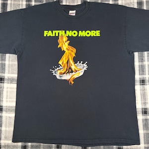 May include: Dark gray t-shirt with the text "FAITH NO MORE" in bright yellow. The shirt features a graphic of flames rising from a bowl of milk. A classic band tee.