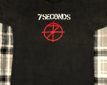 May include: Black t-shirt with a white graphic of the band 7 Seconds and a red target symbol.