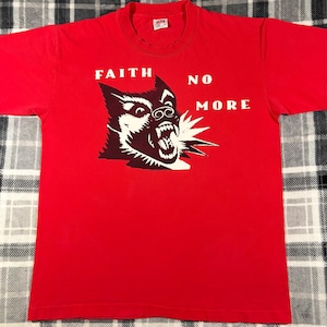 May include: Red t-shirt with the words "FAITH NO MORE" in white block letters above a black and white illustration of a snarling dog. The dog's mouth is open, revealing its teeth.