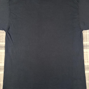 May include: A solid dark navy blue short-sleeved t-shirt featuring a classic crew neckline. The garment is constructed with a standard fit, short sleeves, and a straight hemline, presenting a plain and unadorned surface on the back side.