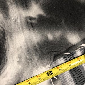 May include: A black and white tie-dye fabric with a yellow measuring tape across the bottom. The tape shows measurements in inches, with numbers from 20 to 26.