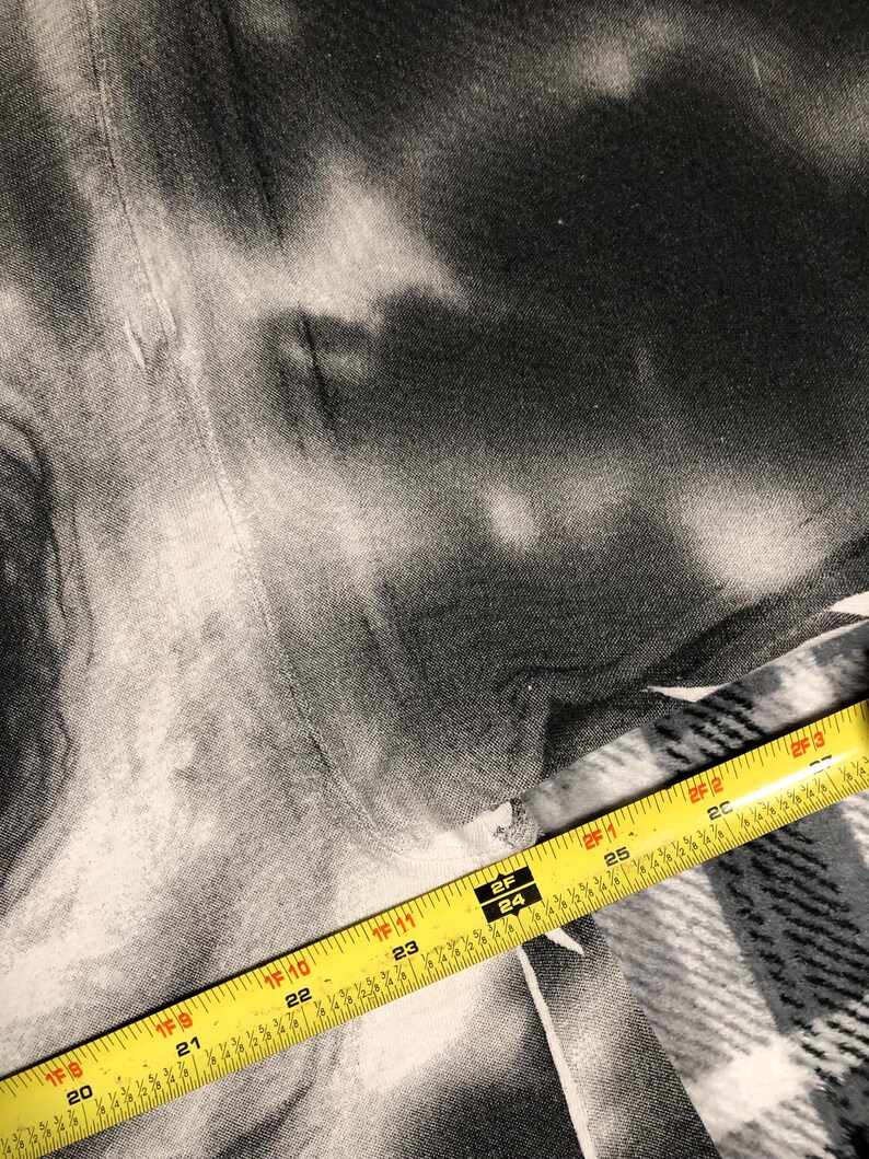 May include: A black and white tie-dye fabric with a yellow measuring tape across the bottom. The tape shows measurements in inches, with numbers from 20 to 26.