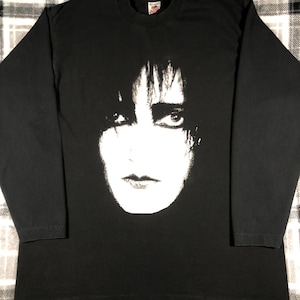 May include: Black long-sleeve t-shirt with a white graphic print of a person's face.