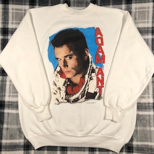 May include: White sweatshirt with a vintage Adam Ant print featuring a close-up image of the singer with the text "ADAM ANT" in red letters.