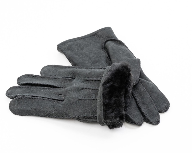 May include: A pair of black leather gloves with a faux fur cuff. The gloves are folded in half and the fur cuff is visible.