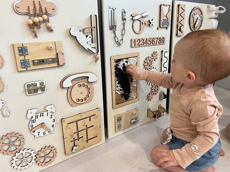 May include: Wooden activity boards featuring interactive elements like latches, gears, a clock, and a sequin panel. Designed for early childhood development and sensory exploration, these boards are a learning tool.