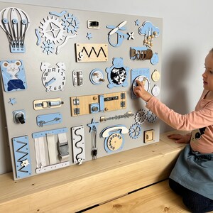 Wall mount busy board for baby with Wooden montessori parts and sensory activities on board. Busy board for 1 year old