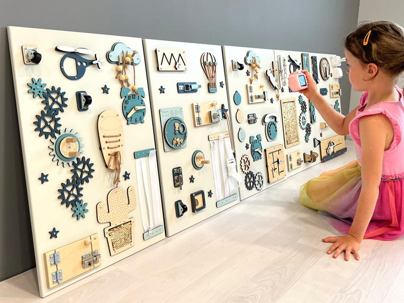 May include: A wooden busy board with multiple panels, featuring interactive elements like gears, clocks, and latches. The board uses blue and natural wood tones, designed for children's sensory exploration and fine motor skill development.