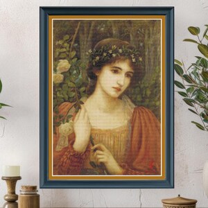 May include: Framed artwork featuring a portrait of a woman with a floral crown and red-orange sleeves. The painting has a dark blue frame with a gold inner border. The woman holds a rose branch against a backdrop of foliage.