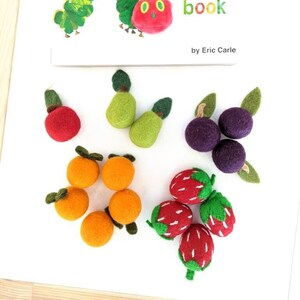 May include: Felt finger puppets of fruits from The Very Hungry Caterpillar's finger puppet book by Eric Carle. The set includes a red apple, two green pears, three purple plums, five orange oranges, and four red strawberries.