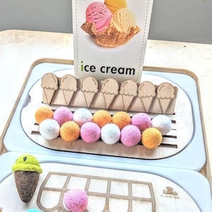 May include: A wooden ice cream stand with a card that says "ice cream" and a picture of ice cream cones. There are 10 small, round, felt balls in various colors, and 8 wooden ice cream cones with a felt ball on top of each cone.