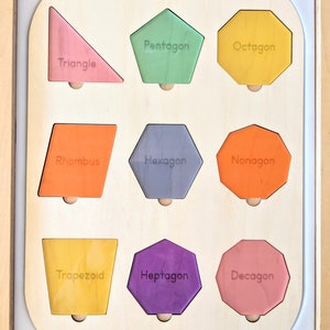 May include: Wooden shape puzzle featuring nine colorful geometric shapes: triangle, pentagon, octagon, rhombus, hexagon, nonagon, trapezoid, heptagon, and decagon. Each shape is labeled with its name and has a wooden peg for easy handling.