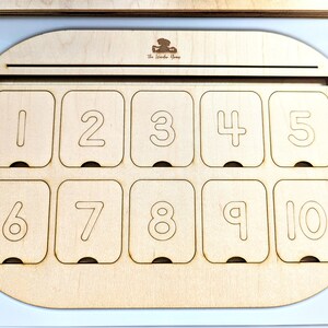 May include: A wooden box with a slot at the top and ten numbered compartments. The compartments are labeled with the numbers 1 through 10.