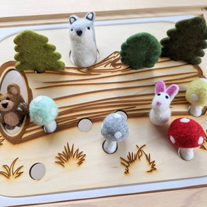 May include: A wooden play set with felt animal and mushroom figures. The set features a brown bear, a wolf, a rabbit, a green tree, and mushrooms with white and red dots.