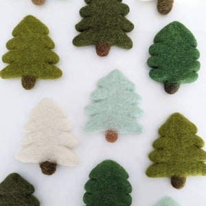 May include: A collection of felt Christmas tree ornaments in various shades of green, white, and blue. The ornaments are all the same size and shape, and they are arranged in a random pattern.